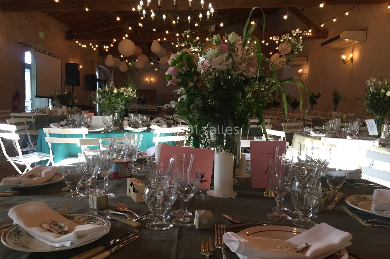 Location salle Pomérols (Hérault) - Domaine Fon de Rey #34 Salle de réception décorée pour un événement, avec tables dressées, fleurs, vaisselle et guirlandes lumineuses suspendues.