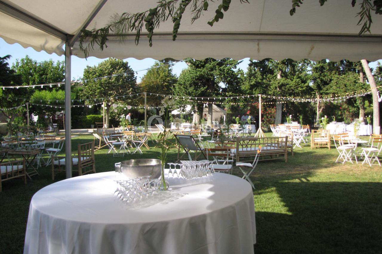 Location salle Pomérols (Hérault) - Domaine Fon de Rey #42 Tables dressées sous une tente dans un jardin, avec guirlandes lumineuses suspendues et végétation en arrière-plan.