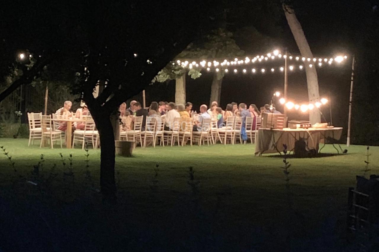 Location salle Pomérols (Hérault) - Domaine Fon de Rey #49 Des personnes dînent en plein air sous des guirlandes lumineuses dans un jardin, en soirée.