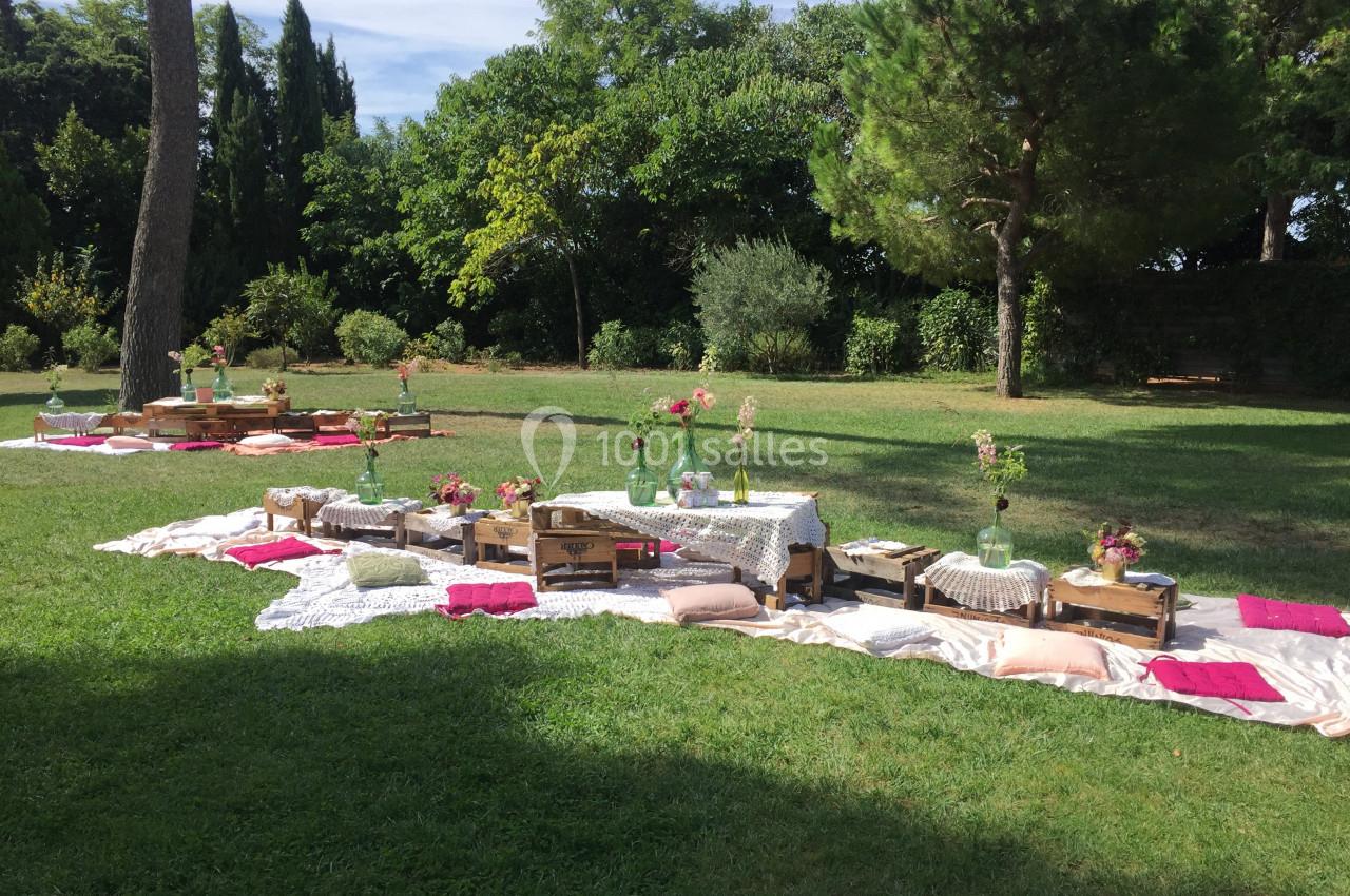 Location salle Pomérols (Hérault) - Domaine Fon de Rey #52 Pique-nique champêtre avec nappes, coussins colorés et tables basses en bois disposés sur une pelouse verdoyante.