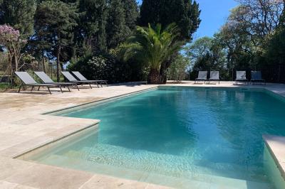 Miniature Location salle Pomérols (Hérault) - Domaine Fon de Rey #64 Piscine extérieure entourée de chaises longues, de végétation luxuriante et de grands arbres sous un ciel bleu.