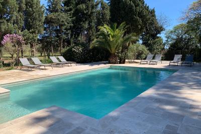 Miniature Location salle Pomérols (Hérault) - Domaine Fon de Rey #65 Piscine extérieure entourée de chaises longues, de végétation luxuriante et de grands arbres sous un ciel bleu.