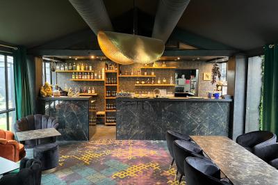 Miniature Location salle Cabriès (Bouches-du-Rhône) - Lodge Le Gaya #4 Intérieur d'un bar élégant avec comptoir en marbre sombre, étagères de bouteilles et fauteuils confortables.