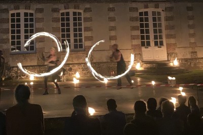 Salon rustique avec murs en pierre, canapés en cuir, table basse et porte ouverte donnant sur un jardin ensoleillé.