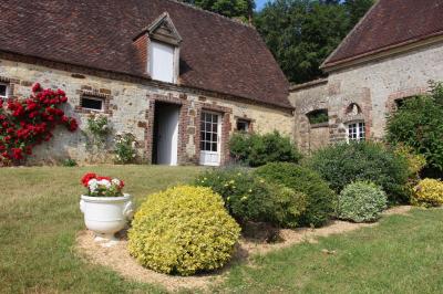 Salon rustique avec murs en pierre, canapés en cuir, table basse et porte ouverte donnant sur un jardin ensoleillé.