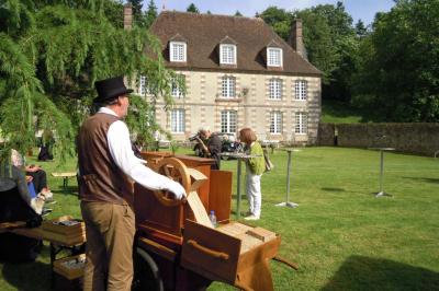 Salon rustique avec murs en pierre, canapés en cuir, table basse et porte ouverte donnant sur un jardin ensoleillé.