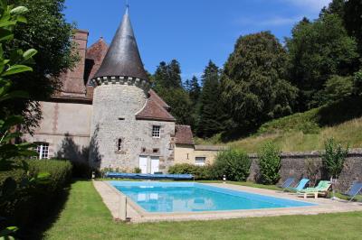 Salon rustique avec murs en pierre, canapés en cuir, table basse et porte ouverte donnant sur un jardin ensoleillé.