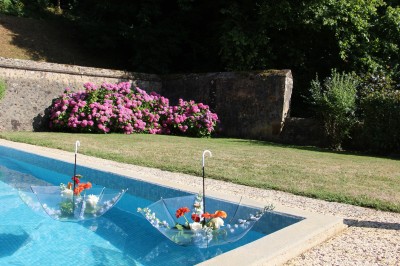 Salon rustique avec murs en pierre, canapés en cuir, table basse et porte ouverte donnant sur un jardin ensoleillé.