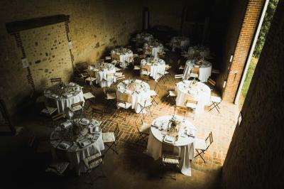 Salon rustique avec murs en pierre, canapés en cuir, table basse et porte ouverte donnant sur un jardin ensoleillé.