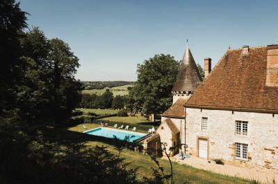 Salon rustique avec murs en pierre, canapés en cuir, table basse et porte ouverte donnant sur un jardin ensoleillé.