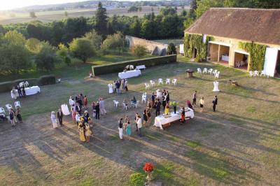 Salon rustique avec murs en pierre, canapés en cuir, table basse et porte ouverte donnant sur un jardin ensoleillé.