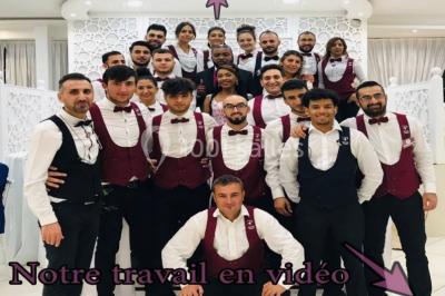 Un groupe de serveurs et serveuses en uniforme posant dans une salle de réception élégante.