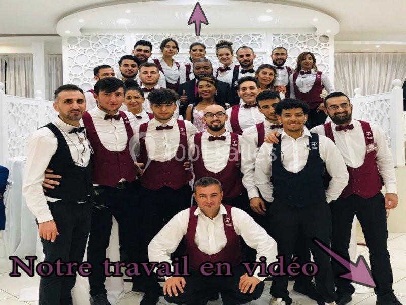 Un groupe de serveurs et serveuses en uniforme posant dans une salle de réception élégante.