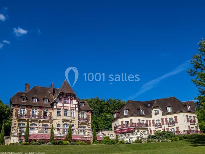 Deux bâtiments de style traditionnel entourés de verdure sous un ciel bleu dégagé.