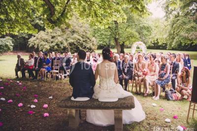 Chambre lumineuse avec parquet en bois, lit double, canapé rouge, table basse et grandes fenêtres avec rideaux fleuris.