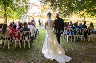 Chambre lumineuse avec parquet en bois, lit double, canapé rouge, table basse et grandes fenêtres avec rideaux fleuris.