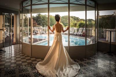 Chambre lumineuse avec parquet en bois, lit double, canapé rouge, table basse et grandes fenêtres avec rideaux fleuris.