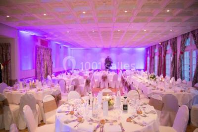 Chambre lumineuse avec parquet en bois, lit double, canapé rouge, table basse et grandes fenêtres avec rideaux fleuris.