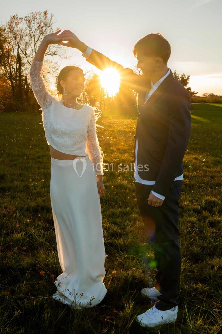 Un couple danse dans un champ au coucher du soleil, la lumière traversant leurs silhouettes.
