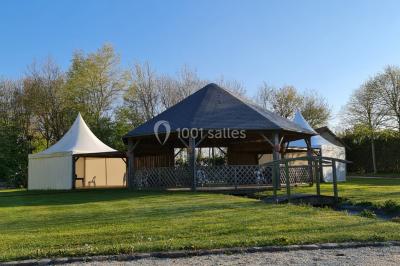 Pressoir ancien en bois dans une pièce avec murs en pierre, plafond à poutres apparentes et sol en parquet.