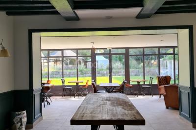 Pressoir ancien en bois dans une pièce avec murs en pierre, plafond à poutres apparentes et sol en parquet.