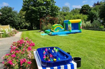 Pressoir ancien en bois dans une pièce avec murs en pierre, plafond à poutres apparentes et sol en parquet.