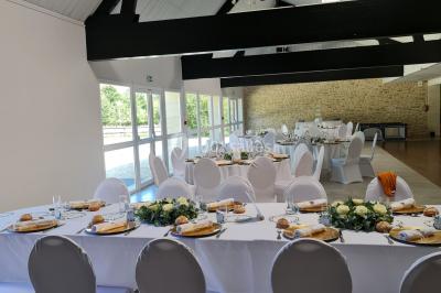 Pressoir ancien en bois dans une pièce avec murs en pierre, plafond à poutres apparentes et sol en parquet.