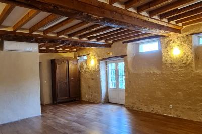 Pressoir ancien en bois dans une pièce avec murs en pierre, plafond à poutres apparentes et sol en parquet.