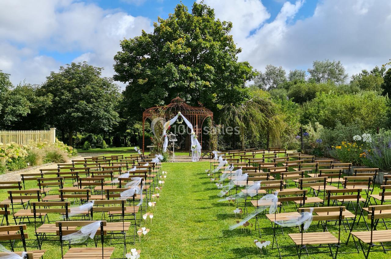 Chaises alignées sur une pelouse menant à une arche décorée pour une cérémonie de mariage en plein air.