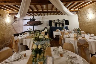 Pressoir ancien en bois dans une pièce avec murs en pierre, plafond à poutres apparentes et sol en parquet.