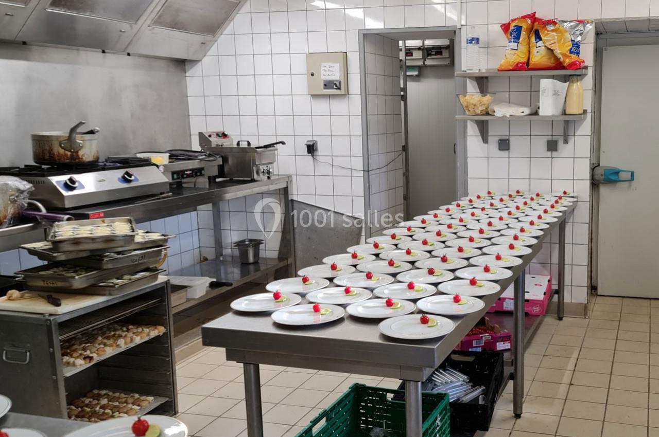 Cuisine professionnelle avec des assiettes alignées sur une table, chacune garnie d'un dessert avec une fraise.