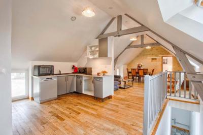Pressoir ancien en bois dans une pièce avec murs en pierre, plafond à poutres apparentes et sol en parquet.