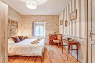 Pressoir ancien en bois dans une pièce avec murs en pierre, plafond à poutres apparentes et sol en parquet.