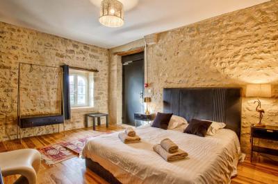 Pressoir ancien en bois dans une pièce avec murs en pierre, plafond à poutres apparentes et sol en parquet.