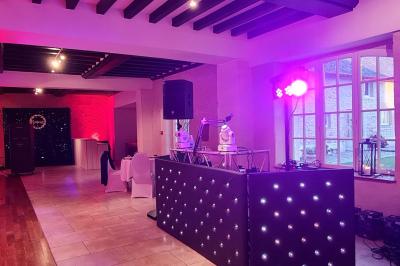 Pressoir ancien en bois dans une pièce avec murs en pierre, plafond à poutres apparentes et sol en parquet.