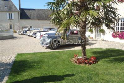 Pressoir ancien en bois dans une pièce avec murs en pierre, plafond à poutres apparentes et sol en parquet.