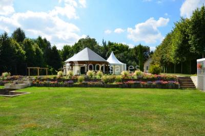 Pressoir ancien en bois dans une pièce avec murs en pierre, plafond à poutres apparentes et sol en parquet.