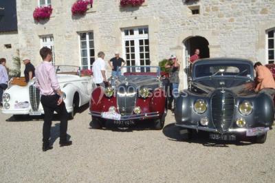 Pressoir ancien en bois dans une pièce avec murs en pierre, plafond à poutres apparentes et sol en parquet.