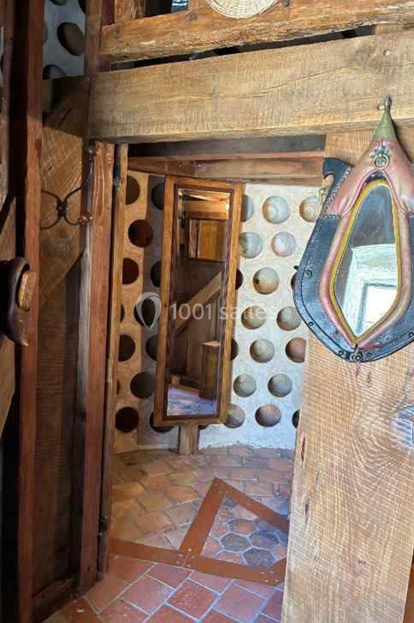 Intérieur en bois avec un miroir, des murs ornés de niches circulaires et un sol en carreaux de terre cuite.