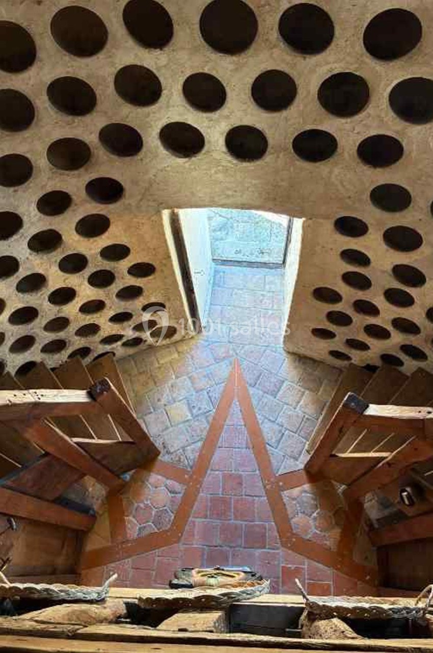Vue intérieure d'un pigeonnier en pierre avec des niches circulaires et un sol en carreaux de terre cuite.