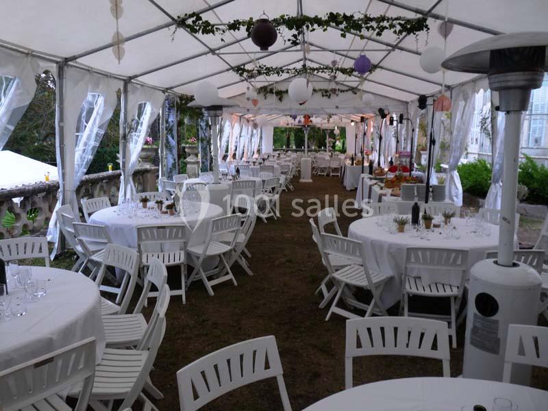 Location salle La Cadière-d'Azur (Var) - Château de Rochebelle - Var #7 Intérieur d'une tente de réception avec des tables rondes dressées, des chaises blanches et des décorations suspendues.