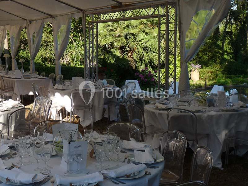 Location salle La Cadière-d'Azur (Var) - Château de Rochebelle - Var #8 Tables élégamment dressées sous une tente blanche, entourées de végétation luxuriante en arrière-plan.
