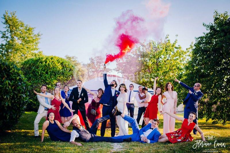 Location salle La Chapelle-Gauthier (Seine-et-Marne) - Nomade-Lodge #5 Un groupe de personnes posant de manière festive dans un jardin, avec une fumée rouge en arrière-plan.