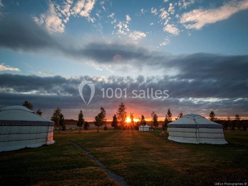Location salle La Chapelle-Gauthier (Seine-et-Marne) - Nomade-Lodge #12 Deux yourtes blanches sur un champ verdoyant au coucher du soleil, avec un ciel partiellement nuageux.