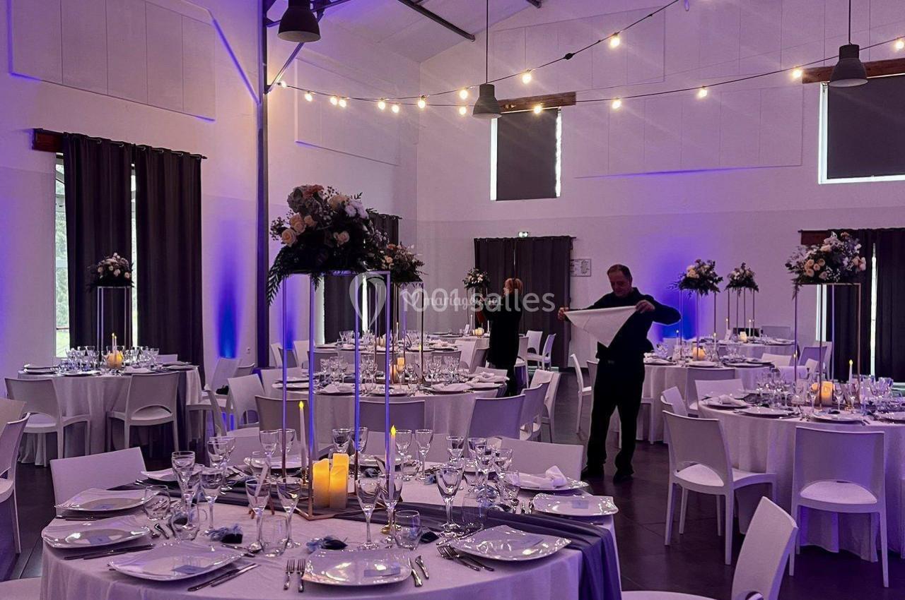 Location salle La Chapelle-Gauthier (Seine-et-Marne) - Nomade-Lodge #36 Salle de réception décorée avec des tables rondes dressées, éclairage tamisé et arrangements floraux élégants.