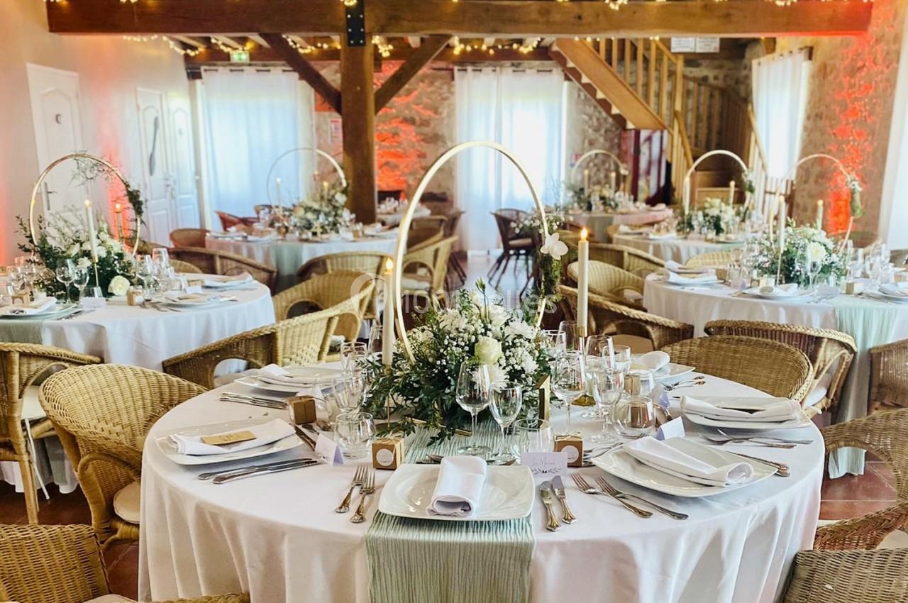 Location salle La Chapelle-Gauthier (Seine-et-Marne) - Nomade-Lodge #33 Salle de réception décorée avec des tables rondes, nappes blanches, compositions florales et bougies, ambiance chaleureuse.