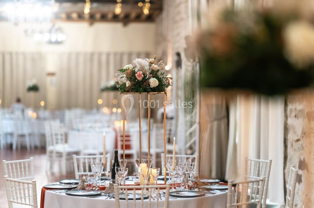 Location salle La Chapelle-Gauthier (Seine-et-Marne) - Nomade-Lodge #64 Table élégamment décorée avec des fleurs, bougies et vaisselle raffinée dans une salle de réception lumineuse.
