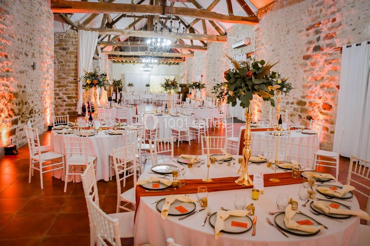 Location salle La Chapelle-Gauthier (Seine-et-Marne) - Nomade-Lodge #69 Salle de réception décorée avec des tables rondes dressées, des chaises blanches et des arrangements floraux élégants.