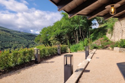 Miniature Location salle Beaujeu (Rhône) - Le Domaine de Vavril #29 Salle voûtée en pierre avec un sol en béton poli, éclairée par des lumières chaudes, et un vase de fleurs au centre.