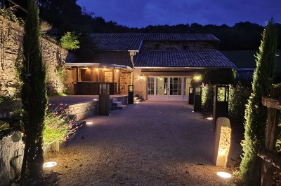 Miniature Location salle Beaujeu (Rhône) - Le Domaine de Vavril #30 Salle voûtée en pierre avec un sol en béton poli, éclairée par des lumières chaudes, et un vase de fleurs au centre.